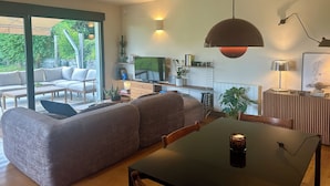 Een moderne woonkamer met een hoekbank, een eettafel en een televisie.