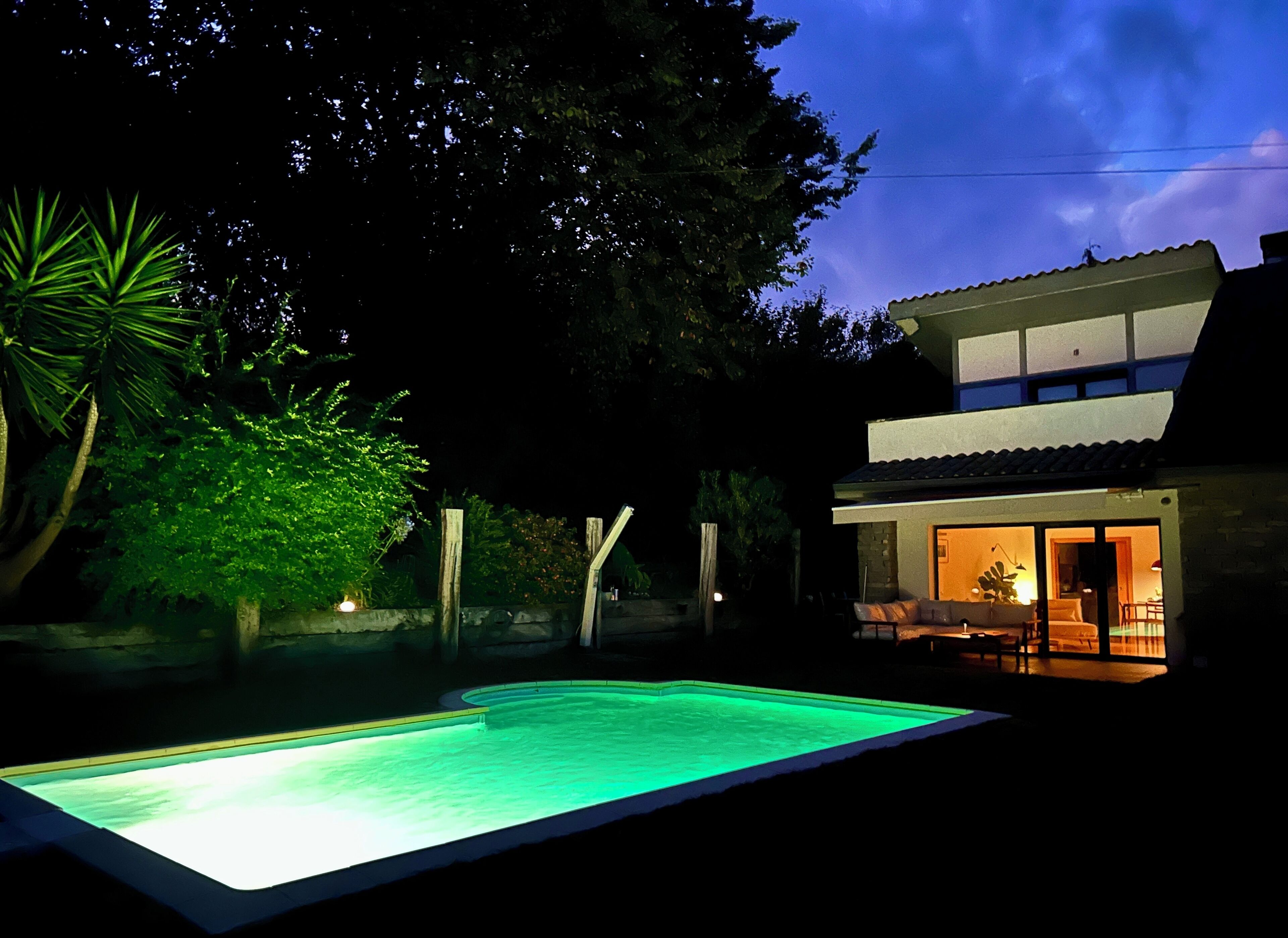 Een tweelaags huis met een zwembad, terras en een goed verlicht interieur.