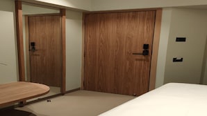 A bedroom with a wooden wardrobe, a bedside table, and a bed. - THE BOHOO 99 (Mumbai)