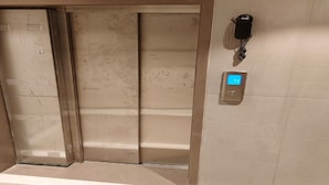 An elevator with a digital display and a phone mounted on the wall. - THE BOHOO 99 (Mumbai)
