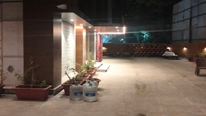 An outdoor area with a concrete floor, potted plants, and large water containers. - THE BOHOO 99 (Mumbai)