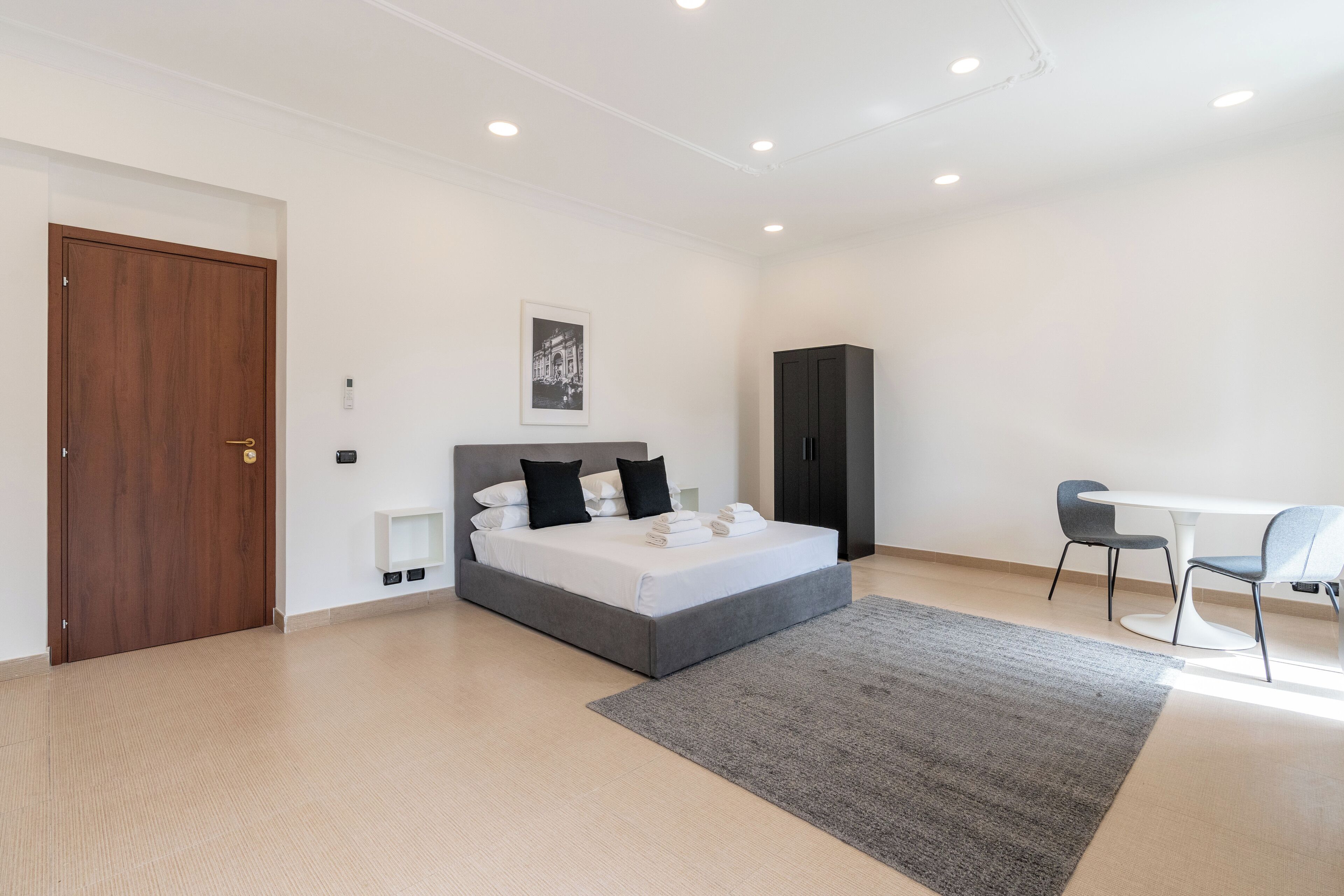A modern bedroom with a bed, a desk, and a wardrobe.