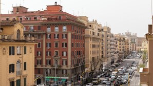 Vista de una calle en la ciudad con edificios altos, autos estacionados y cielo despejado.