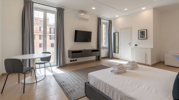 Una habitación de hotel moderna con cama, televisor, escritorio y vista a la ciudad.