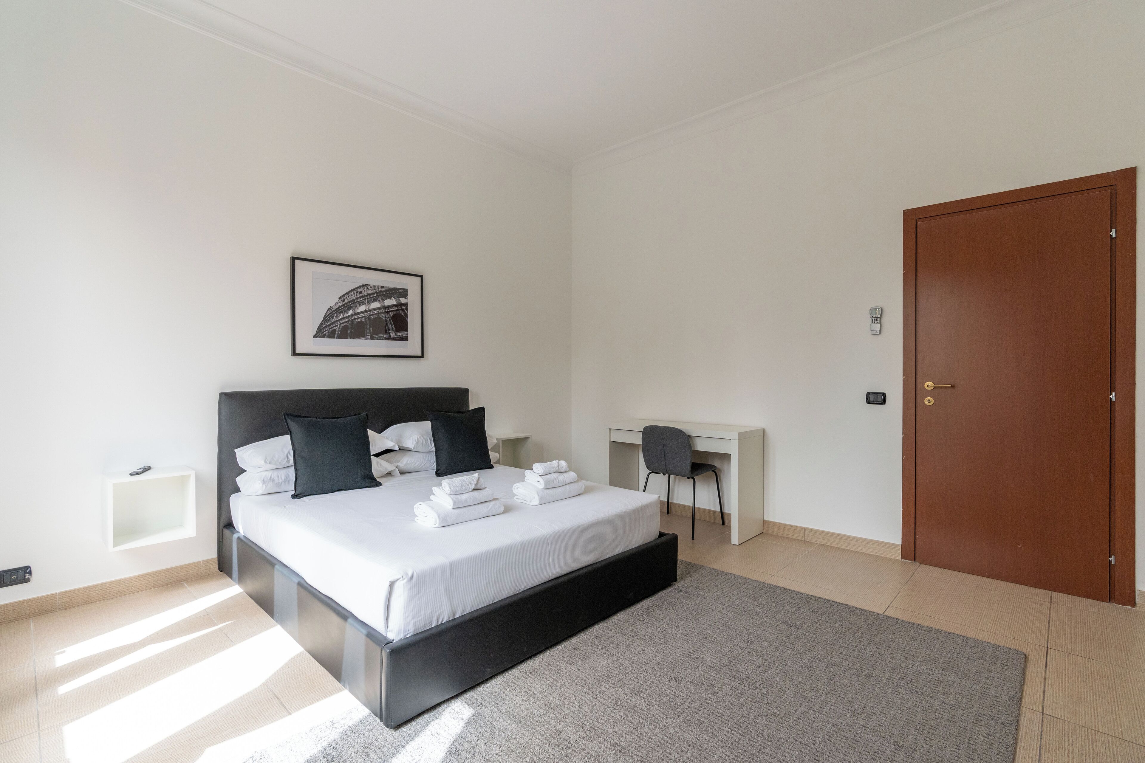 Une chambre moderne avec un grand lit, un bureau et une armoire.