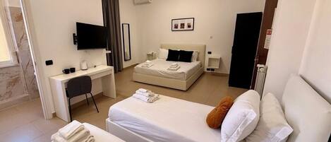 Une chambre d’hôtel avec deux lits, un bureau, une télévision et un petit coin salon.