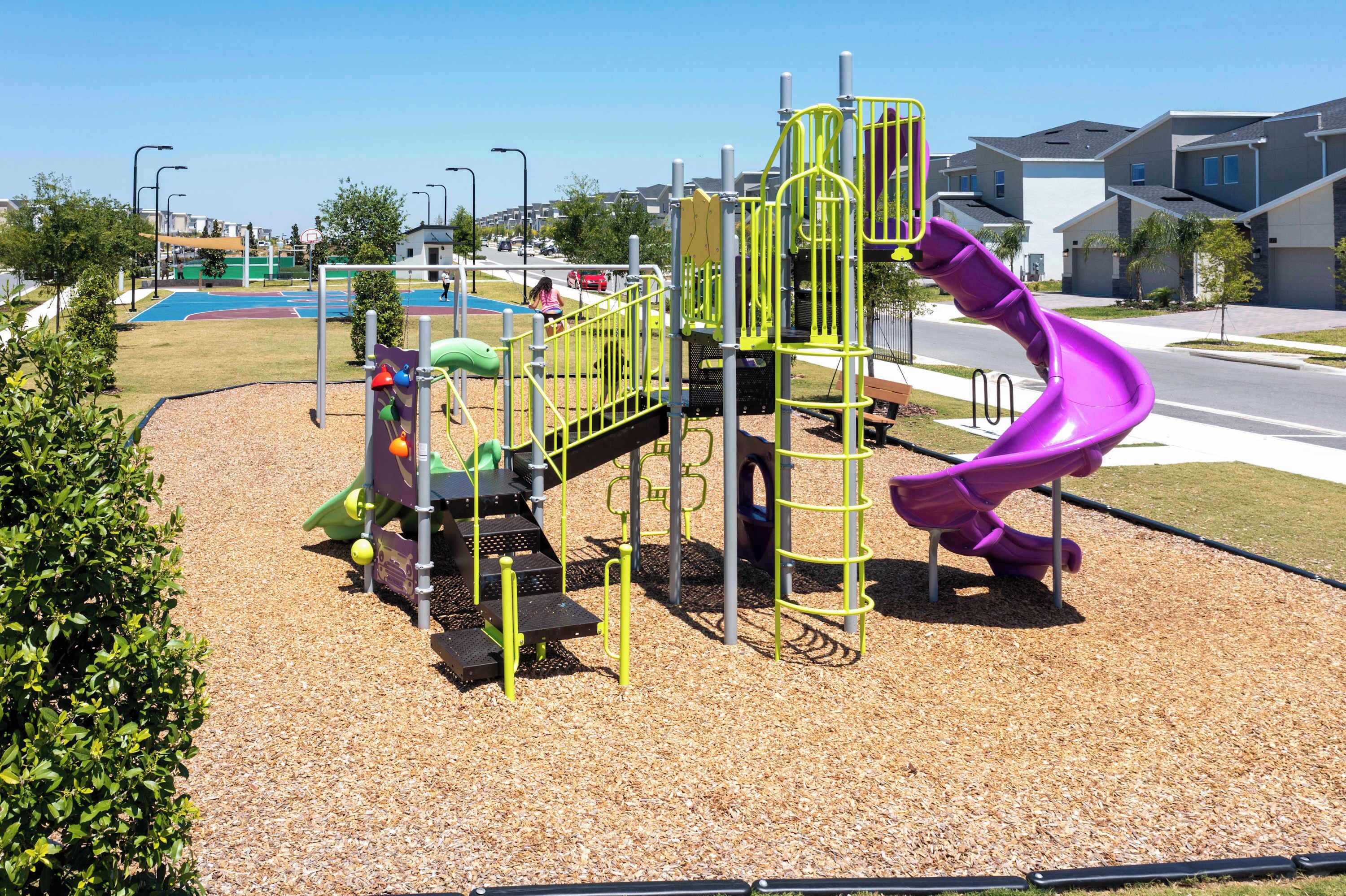 Une aire de jeux avec un toboggan violet et des structures d’escalade.