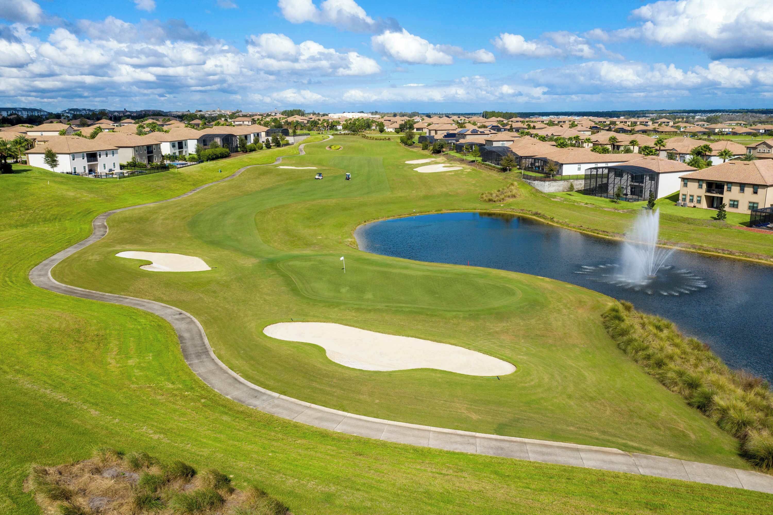 Egy golfpálya, melynek része homokakadályok, egy tó és egy szökőkút.