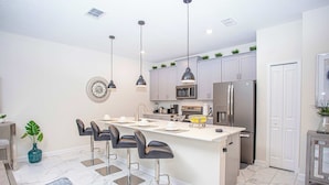 A modern kitchen with a central island, stainless steel appliances, and bar stools. - Marvelous 4 Bd w Pool Waterpark Near Disney 218 (Kissimmee)