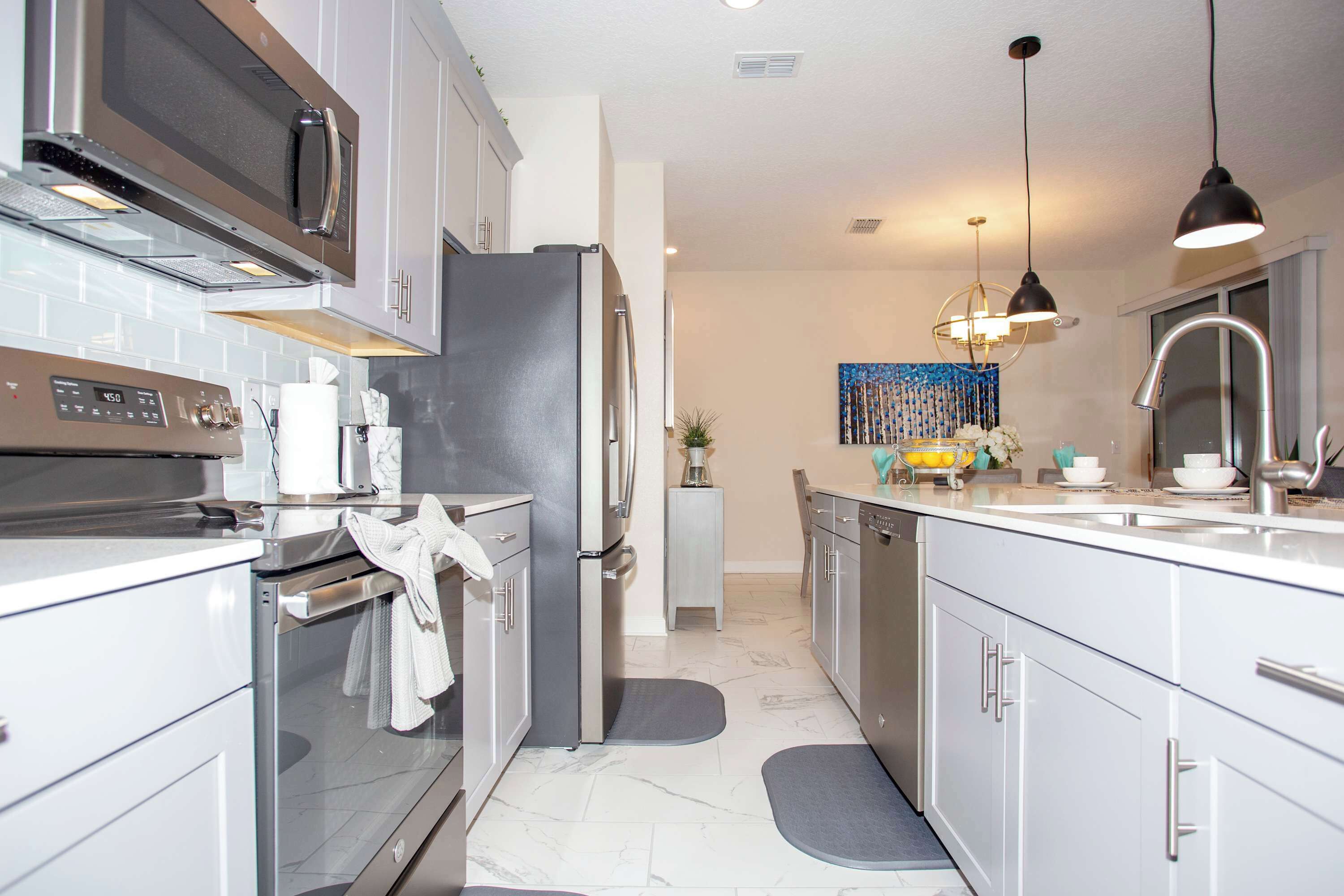 A modern kitchen with stainless steel appliances, a central island, and pendant lighting.