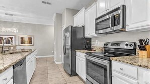 A modern kitchen with white cabinets, stainless steel appliances, and granite countertops. - Paradise 4Bd w Private Pool Waterpark 8951 (Kissimmee)