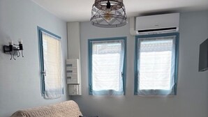 Ett litet, modernt vardagsrum med en soffa, ett matbord och två fönster med blå ramar.