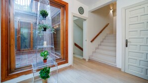 A staircase leading to a second floor, a clear glass shelf with potted plants, and a white door with a wooden frame. - P Casa Cafe Madrid Calle Carlos Dubois 3 (Madrid)
