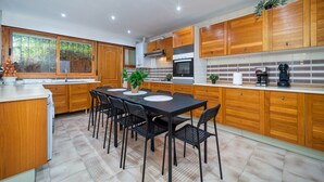 A modern kitchen with wooden cabinets, a dining table with chairs, and a large window. - P Casa Cafe Madrid Calle Carlos Dubois 3 (Madrid)