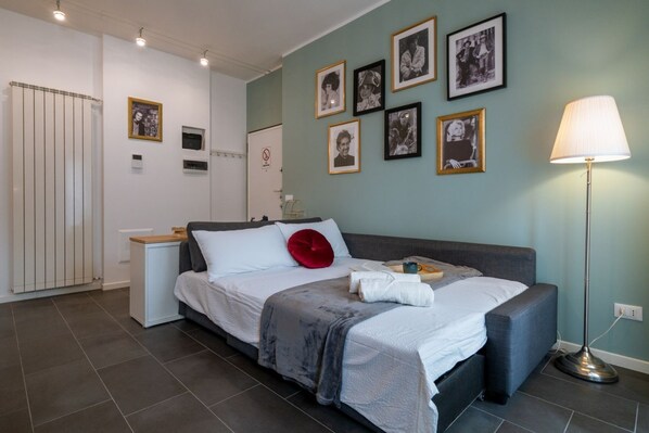 Une chambre à coucher moderne avec un lit, des tables de chevet, une lampe et des tableaux encadrés accrochés au mur.
