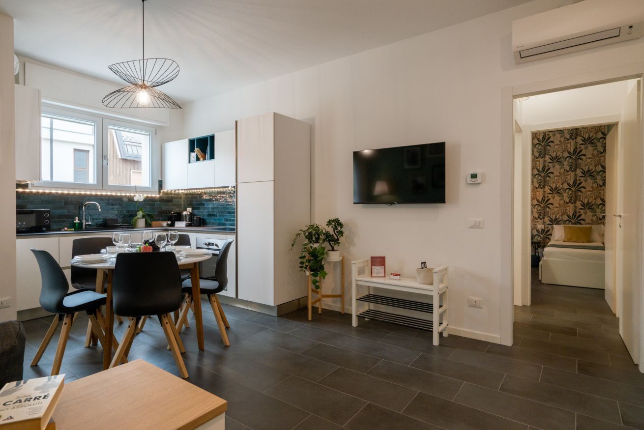 Eine moderne Küche mit Essbereich, einem Flachbildfernseher und einer Treppe, die zu einem Schlafzimmer führt.