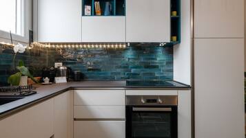 Una cocina moderna con armarios blancos, horno negro y salpicadero azul.