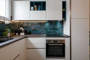 A modern kitchen with white cabinets, a black oven, and a blue backsplash.