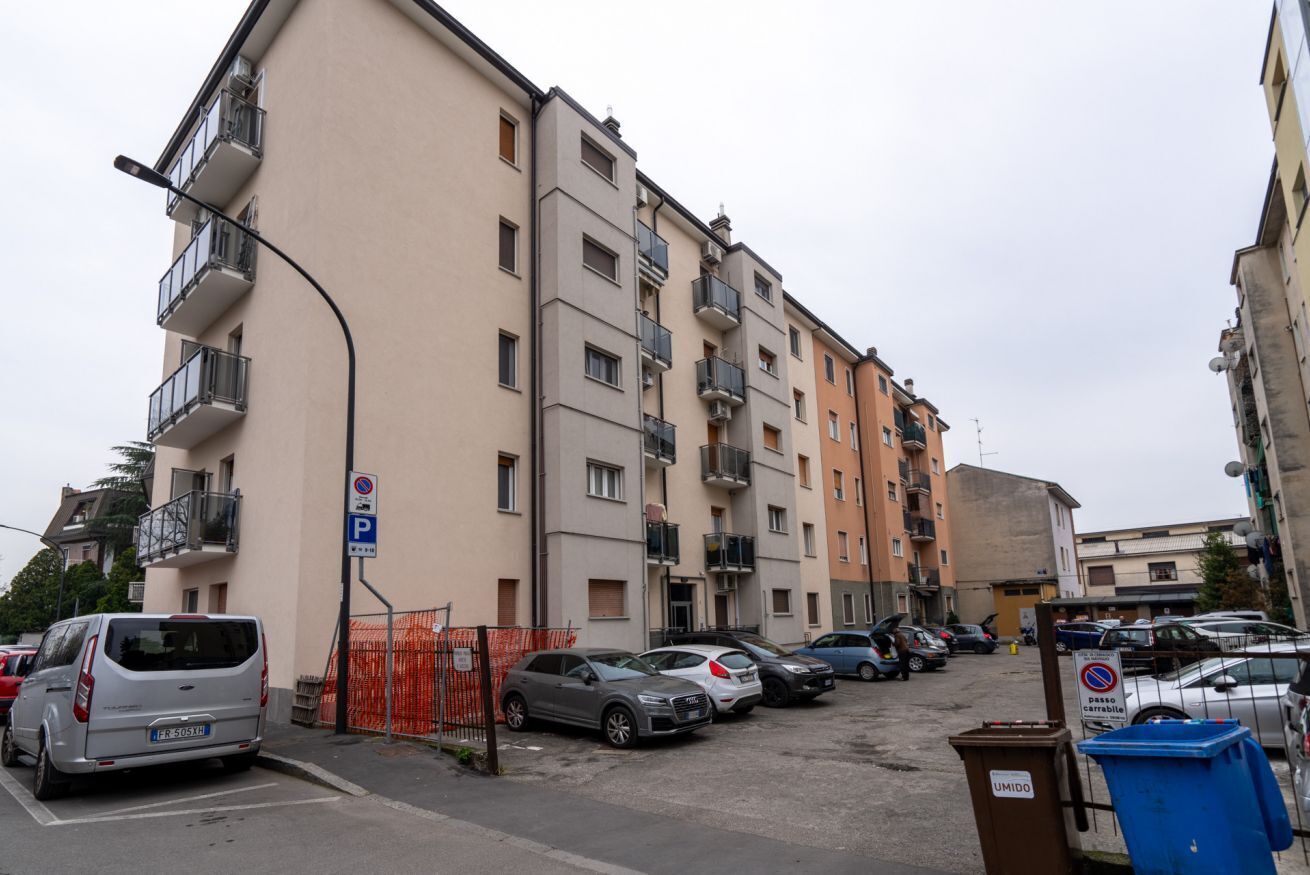 Un edificio residenziale a più piani con balconi, un'area parcheggio e un lampione.