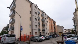 En flereetagers boligbygning med altaner, parkeringsplads og en gadelampe.