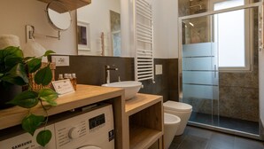 Et moderne badeværelse med en trækommode, en hvid vask, toilet, en glasbrusekabine og en digital frekvensomformer.
