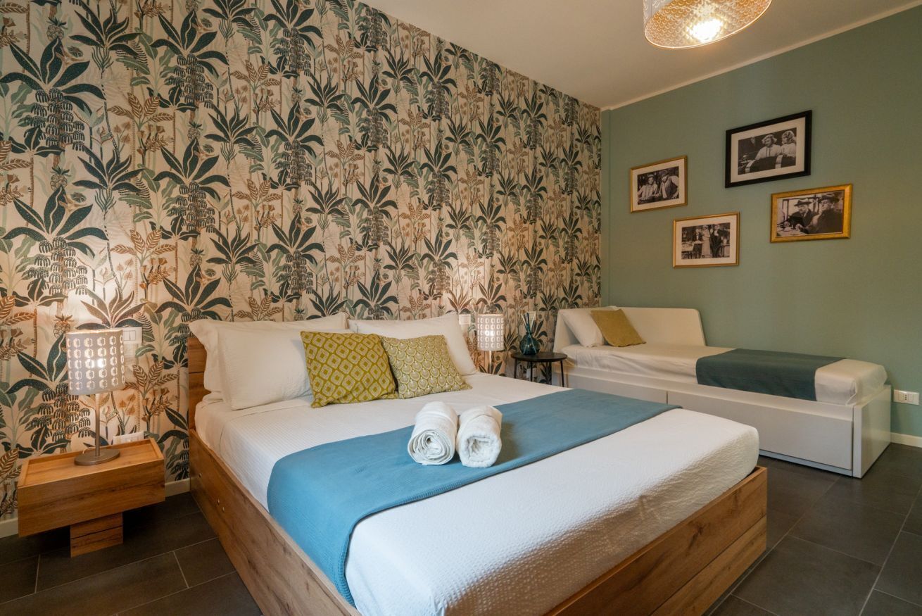 Een slaapkamer met een bed, nachtkastjes, een bank en een muur met ingelijste foto's.