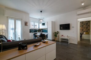 A modern living room with a sofa, a wooden coffee table, a TV, and a dining area with a table and chairs.
