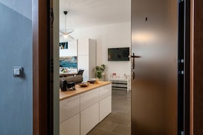 Una cocina moderna con armarios blancos, encimera de madera y un comedor con mesa y sillas.