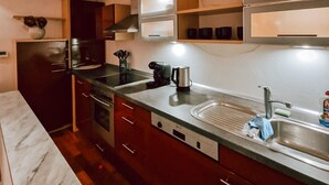 Une cuisine compacte avec des meubles en bois foncé, un évier en acier inoxydable et un four encastré.