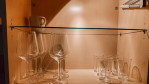 Une étagère en bois avec plusieurs verres à vin et une petite tasse.