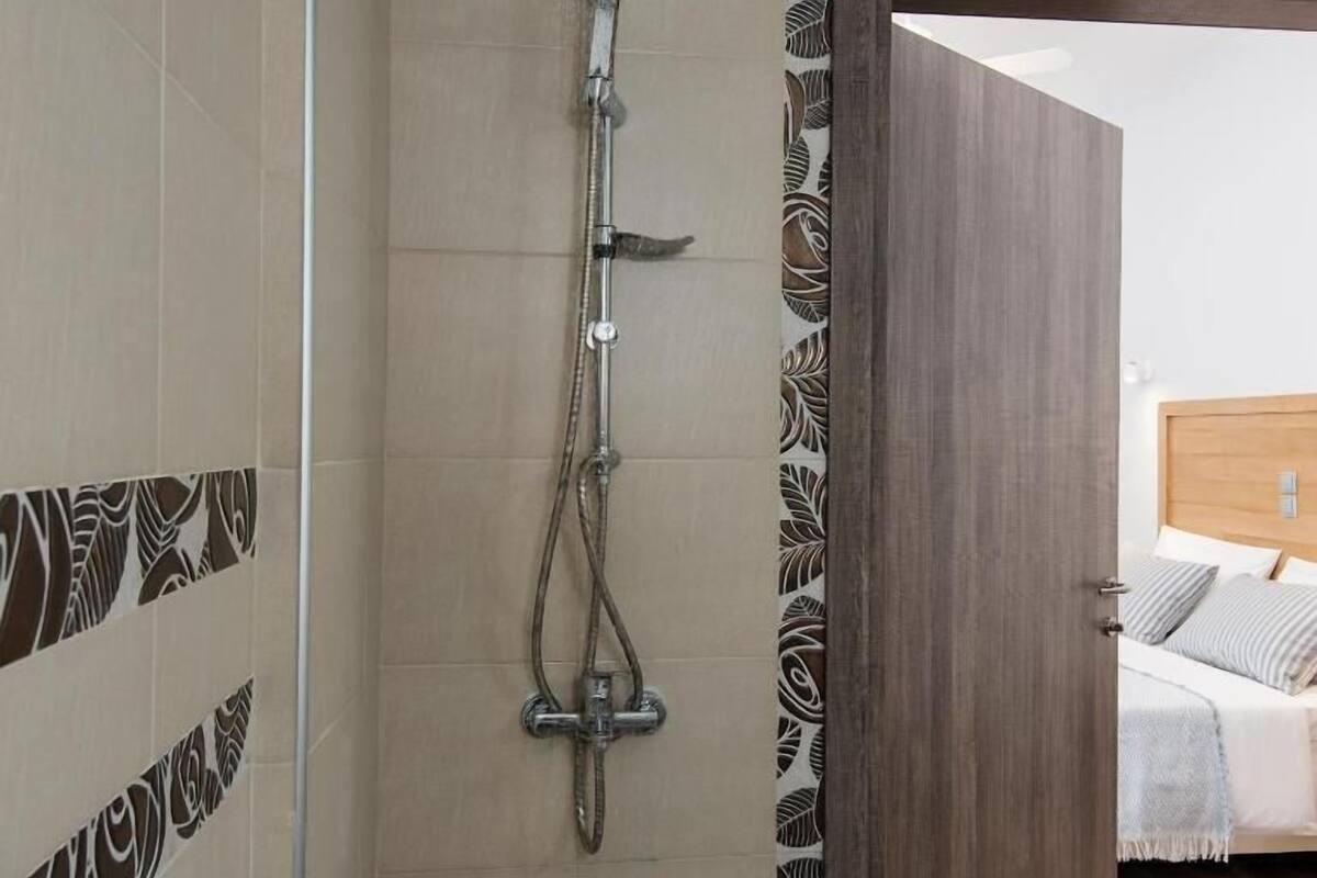 A shower with a rain shower head, a handheld showerhead, and a handheld scrubber.