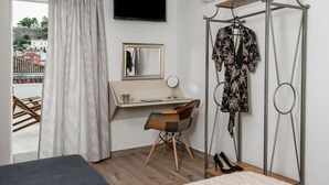A bedroom with a bed, a desk, a chair, a hanging clothes rack, and a window with curtains. - Downtown Hotel (Nafplio)