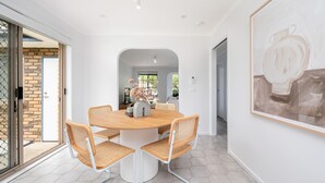 Ein Essbereich mit einem runden Tisch, vier Korbstühlen und einem großen, abstrakten Gemälde an der Wand.