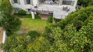 Ein modernes, zweistöckiges Haus mit einer Terrasse und Gartenmöbeln.