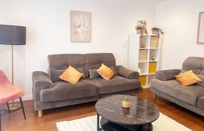 A living room with two grey sofas, a round black coffee table, a pink chair, and a bookshelf with decorative items. - Belle in 15 mts Triumphal Arch (Paris)