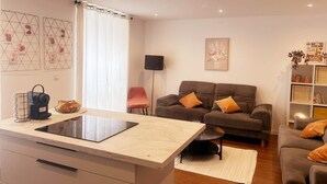Un salon moderne comprenant un canapé, une table basse et un coin cuisine avec un plan de travail et une bouilloire.