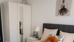 Une chambre à coucher avec un grand lit, une table de chevet avec une lampe, une armoire et un tableau encadré au mur.