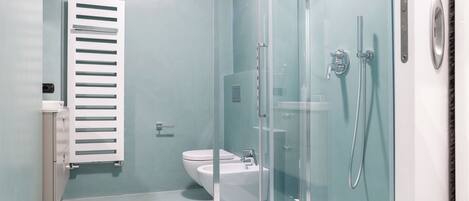 A modern bathroom with a glass shower enclosure, a toilet, and a sink.