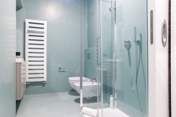 A modern bathroom with a glass shower enclosure, a toilet, and a sink. - MG Home (Como)