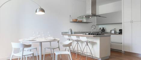 A modern kitchen with a central island, white chairs, and a round dining table.