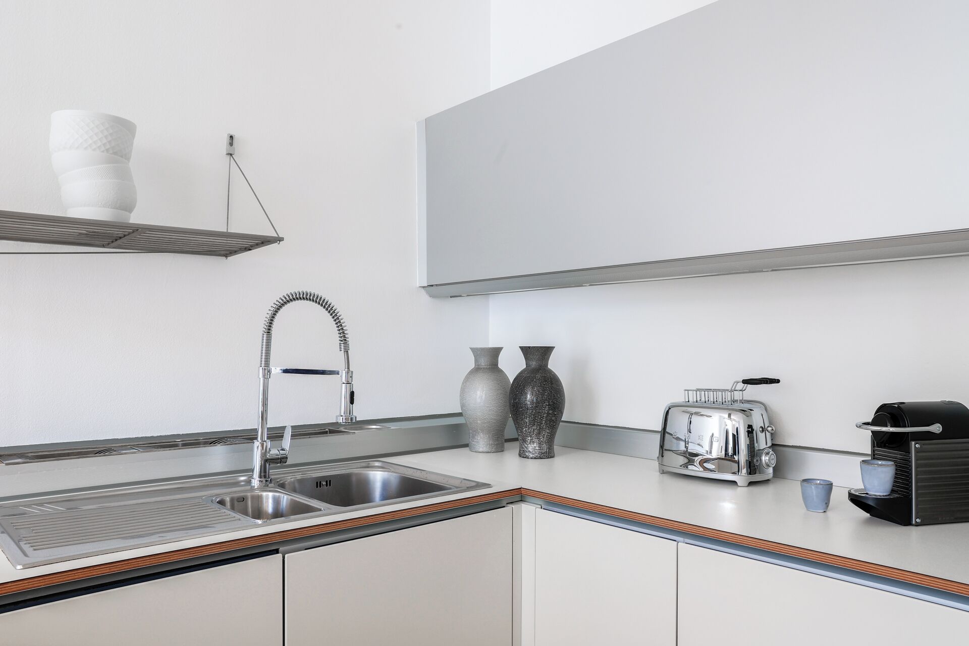 Una cocina moderna con un lavamanos de acero inoxidable, un tostador y una cafetera.