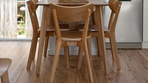 A wooden dining table with chairs in a modern kitchen with white walls and a view of greenery outside. - Prickly Pear Stays in Merewether - Ridge St (Newcastle)