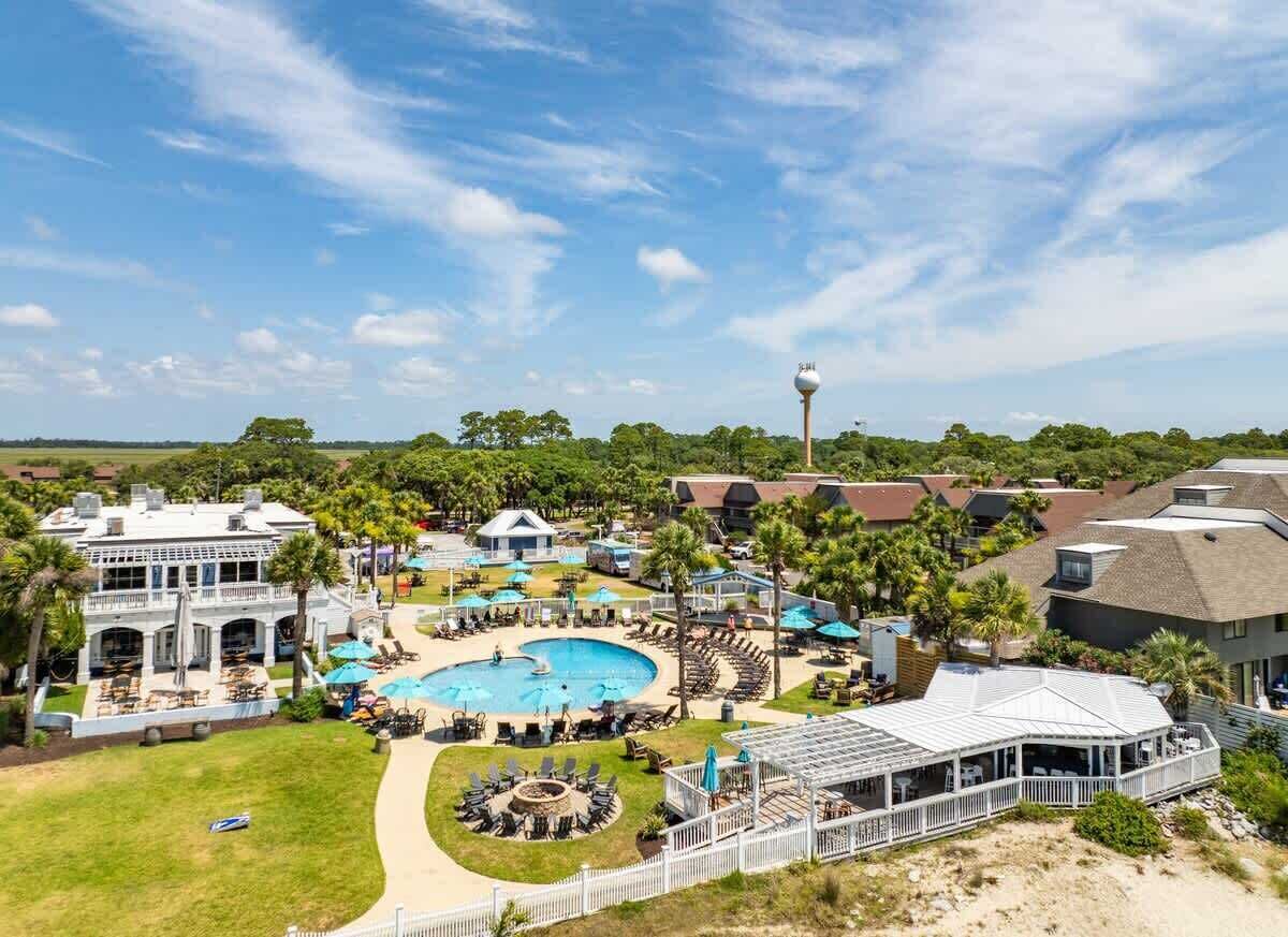 A resort with a swimming pool, outdoor seating, and a covered area.