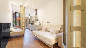A modern living room with a sofa, a small table, and a kitchen area in the background. - Apartment 'Mestalla Flats Rut' with Private Terrace, Wi-Fi and Air Conditioning (Valencia)