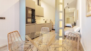 A modern kitchen with built-in appliances, a glass dining table with wicker chairs, and a bedroom with a bed and a nightstand. - Apartment 'Mestalla Flats Rut' with Private Terrace, Wi-Fi and Air Conditioning (Valencia)