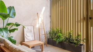 A modern outdoor seating area with a wooden table, a cushioned bench, and a ladder leaning against a wall. - Apartment 'Mestalla Flats Rut' with Private Terrace, Wi-Fi and Air Conditioning (Valencia)