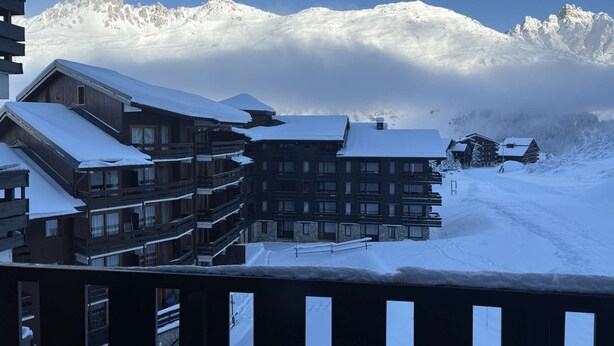 A snow-covered mountain resort with multi-story buildings, including a hotel with balconies and a ski lodge. - Cosy apartment ski-in/ski-out (Les Allues)