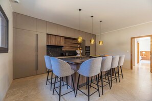 A modern kitchen with a central island, bar stools, pendant lights, and built-in appliances. - Villa Anna - 10 minutes from the beach (Bonifacio)