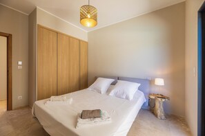 A neatly made bed with white linens, a wooden wardrobe, a hanging light fixture, and a small wooden side table with a lamp. - Villa Anna - 10 minutes from the beach (Bonifacio)