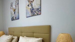 A bedroom with a bed, pillows, a headboard, a bedside table with a lamp, and two wall-mounted paintings. - Stylish Taksim 360 Apartment in Central Istanbul (Beyoğlu)